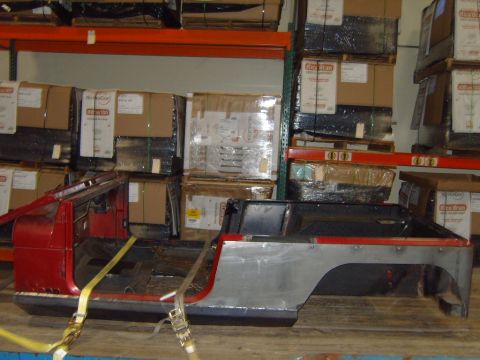 1985 Jeep CJ7 - The body of a Jeep CJ is secured with straps on a pallet in a storage facility.