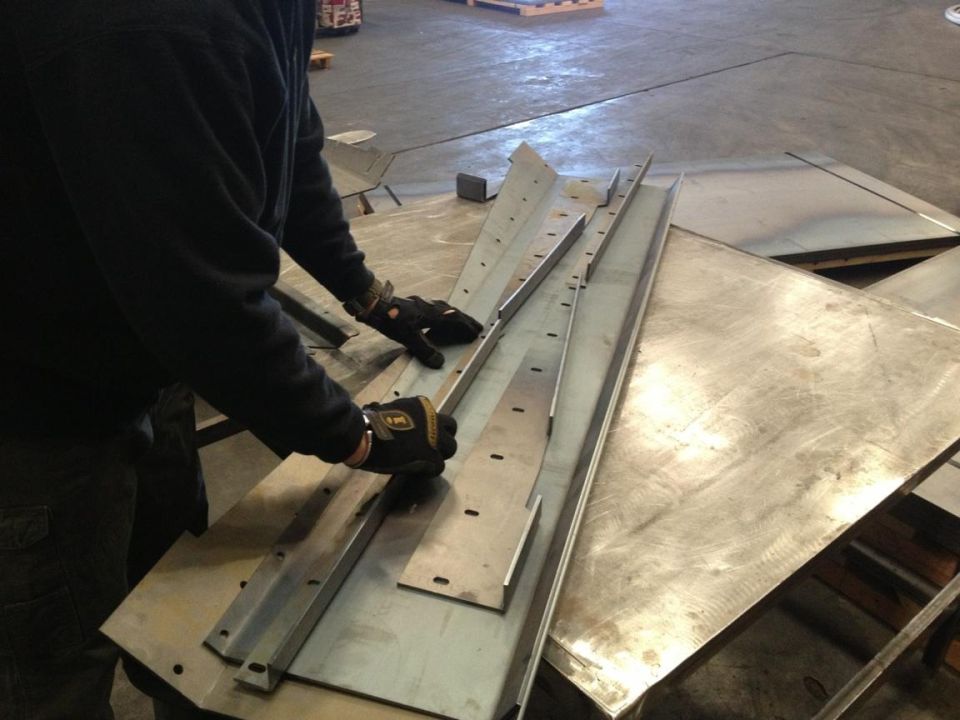 Person in gloves handling metal pieces with pre-drilled holes