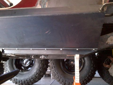 1985 Jeep CJ7 - Close-up view of the undercarriage and large tires of a vehicle, supported by jack stands.