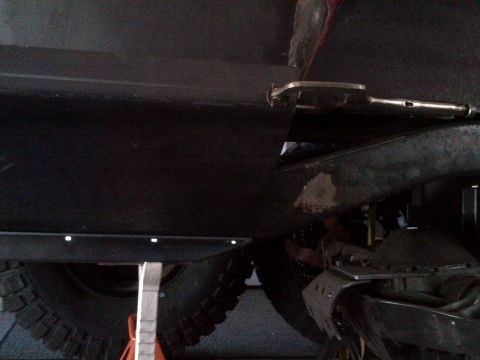 1985 Jeep CJ7 - Underside view of a vehicle, showing the tire and suspension system with some metal plating.