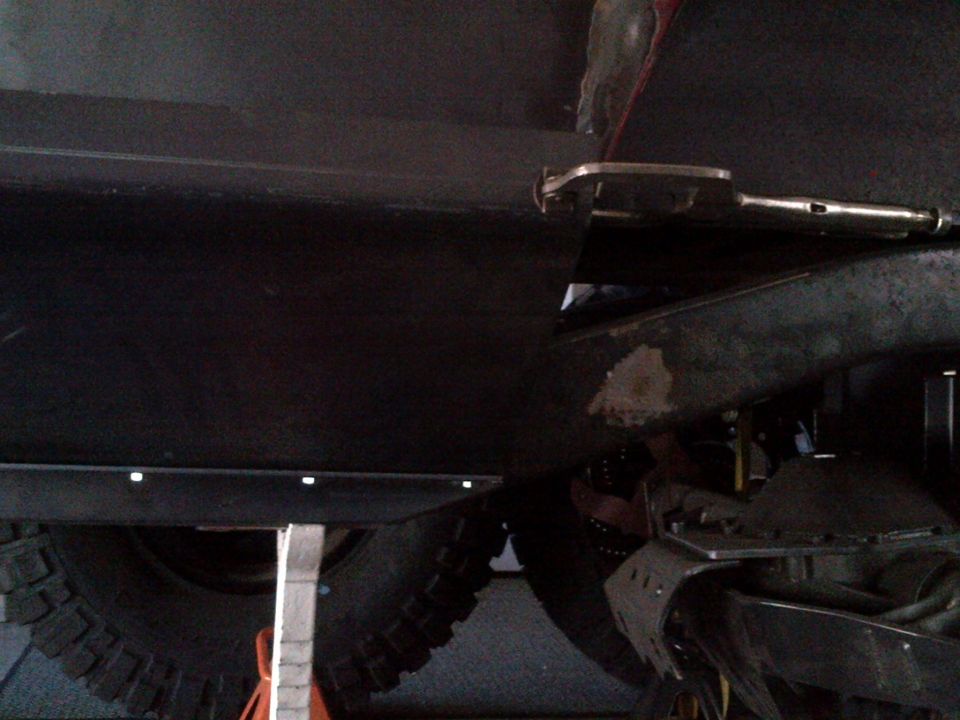 close-up of vehicle undercarriage with large tire and suspension components visible