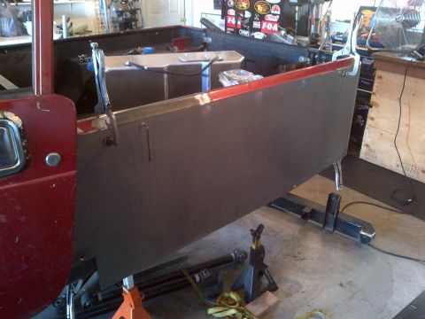 1985 Jeep CJ7 - A red Jeep CJ body panel is being worked on in a garage setting.
