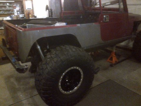1985 Jeep CJ7 - This 1985 Jeep CJ7 body is undergoing work in a garage, showing its side profile and large tire.