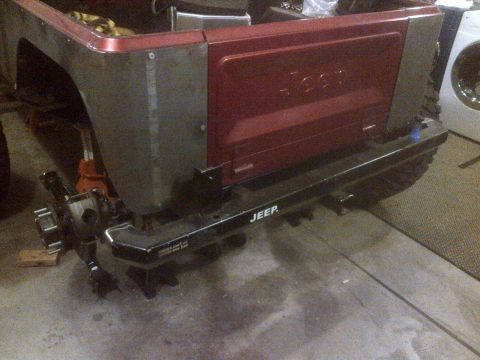 1985 Jeep CJ7 - The rear section of a red Jeep is visible, the tailgate and a black bumper with "JEEP" branding.