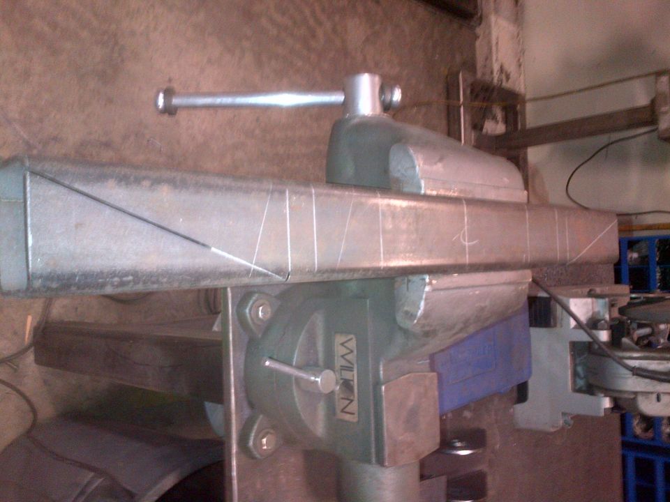 metal bar clamped in a vise with chalk marks