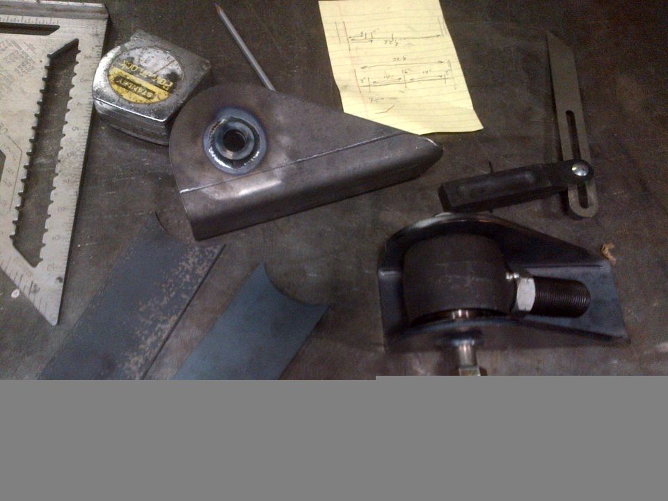 Metal fabrication parts, tape measure, and drafting square on a workbench