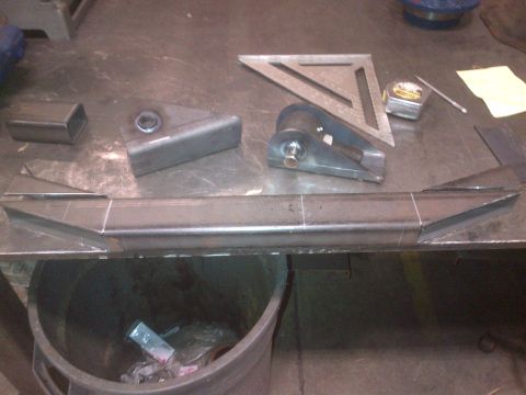 1985 Jeep CJ7 - Fabrication parts are laid out on a workbench, ready for assembly, alongside a speed square and tape measure.