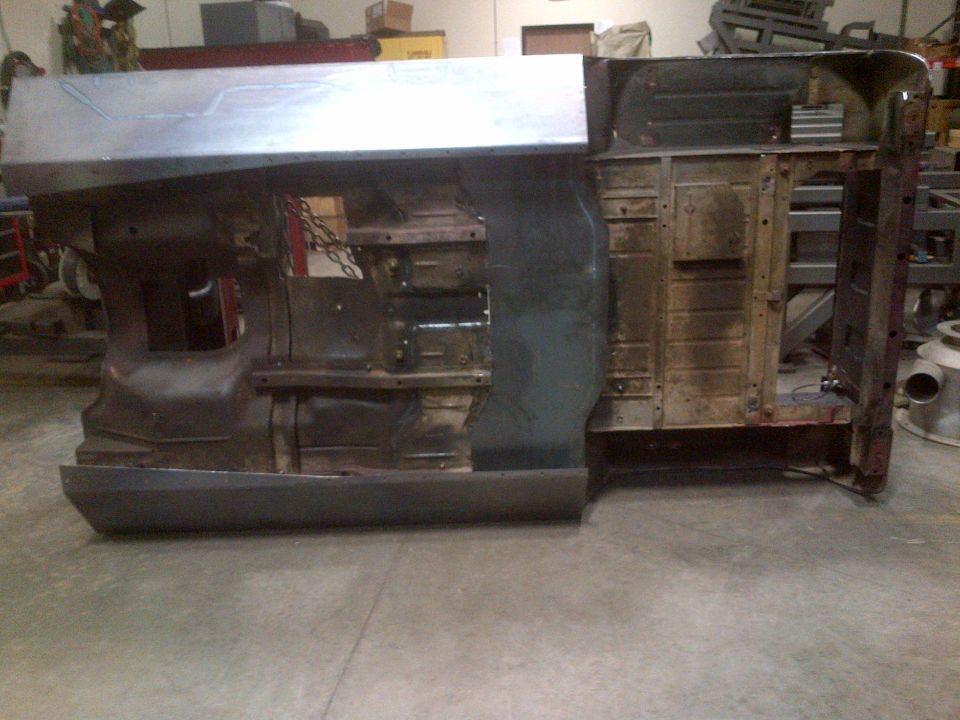 Jeep CJ body shell upside down, showing underside and some interior panels. It's in a workshop setting