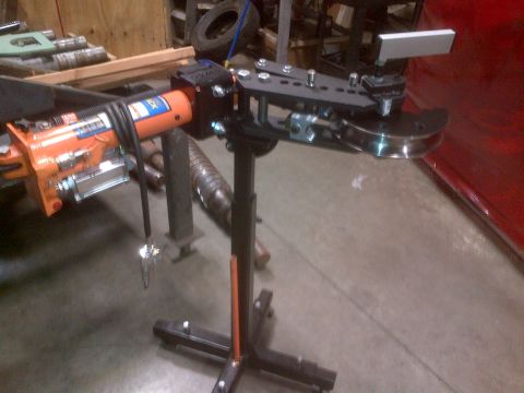 1985 Jeep CJ7 - A hydraulic tube bender with an orange cylinder and black metal frame is shown in a workshop setting.