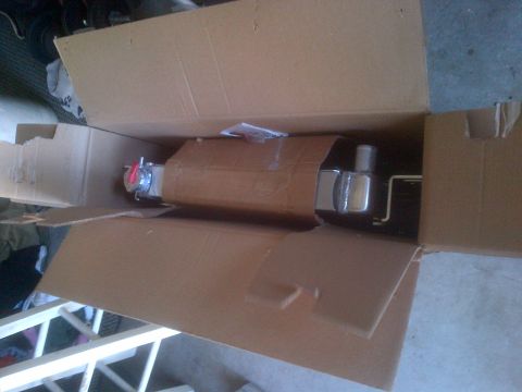 1985 Jeep CJ7 - An exhaust pipe is shown inside a cardboard box, with some packaging material visible.