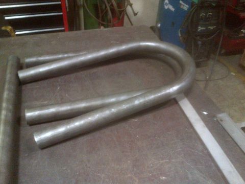 1985 Jeep CJ7 - Bent metal tubes are seen on a workbench, with welding equipment visible in the background.
