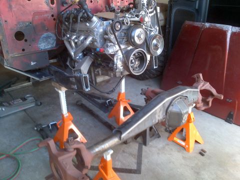 1985 Jeep CJ7 - Vehicle chassis and engine components are disassembled and supported by jack stands in a workshop.