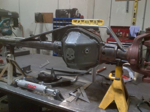 1985 Jeep CJ7 - Custom differential housing with skull cover and steering stabilizer in a workshop setting.