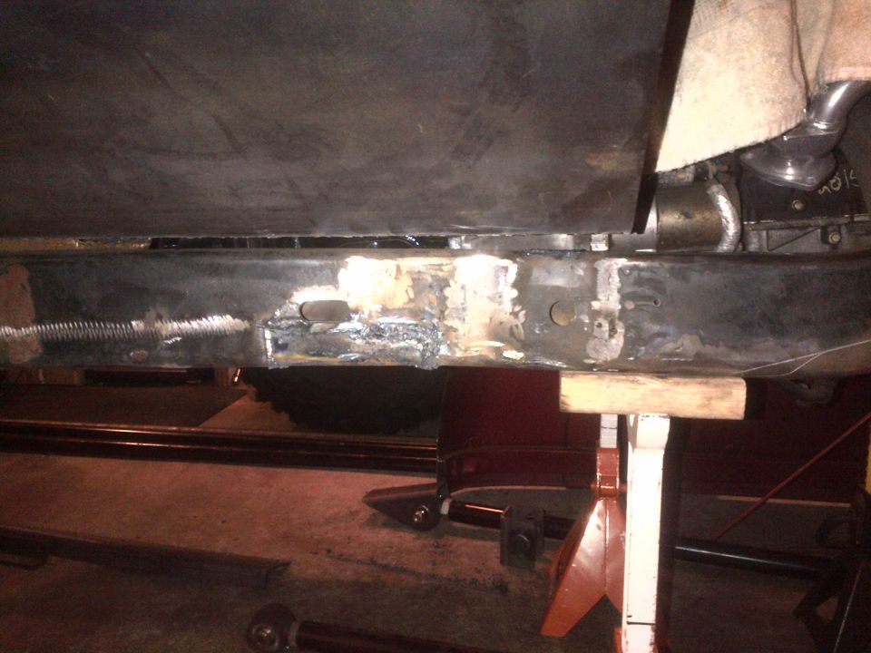 frame rail with fresh welds and some rust damage, supported by jack stands and wood blocks