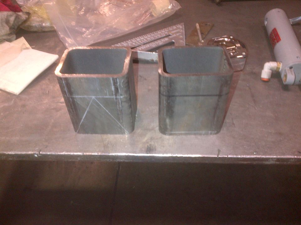 Two square metal tubes with scribe lines on a workbench