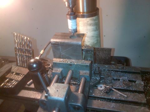 1985 Jeep CJ7 - A metal part is being worked on by a drill press on a milling machine, surrounded by metal shavings.