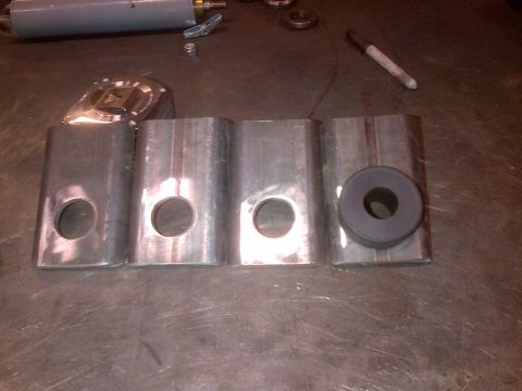 1985 Jeep CJ7 - Several metal components, possibly for a vehicle modification, are laid out on a work surface.