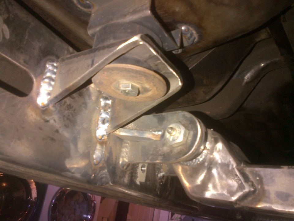 Close-up of custom welded suspension brackets on a vehicle frame, showing bolts and washers