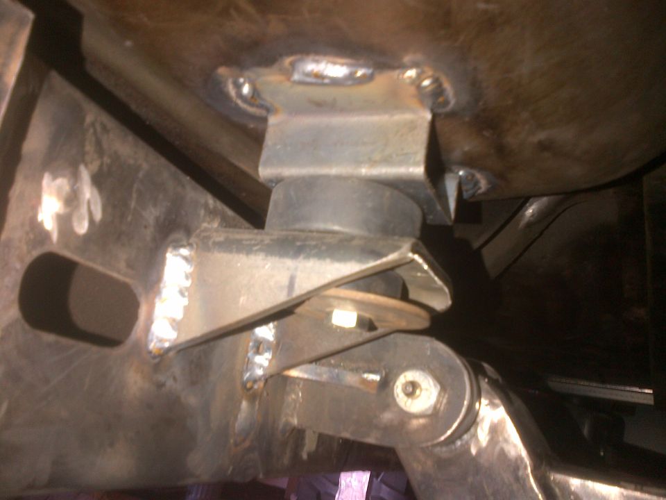 Close-up of a suspension mount with a rubber bushing and visible welds