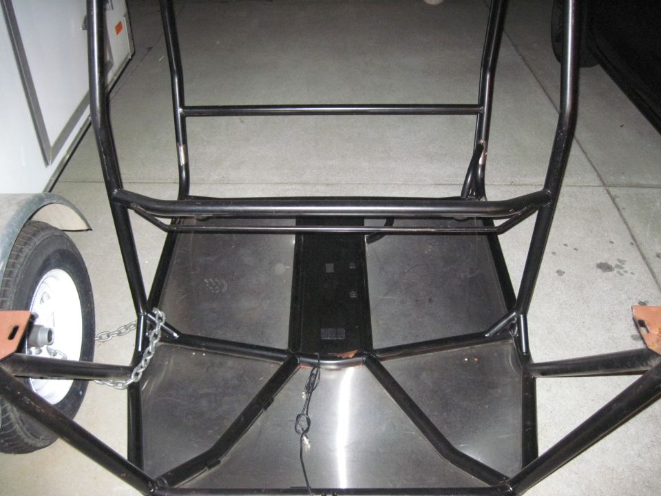 roll cage frame with metal floor panels and trailer wheel on left