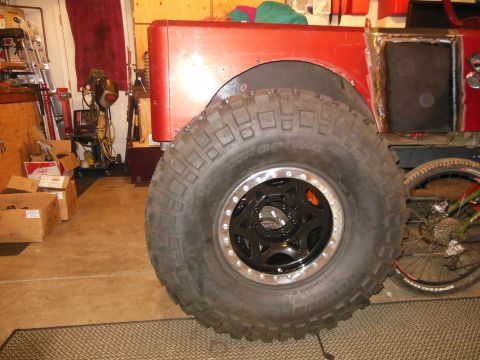 1985 Jeep CJ7 - This red Jeep CJ7 is shown from the side, oversized off-road tires and custom black wheels.