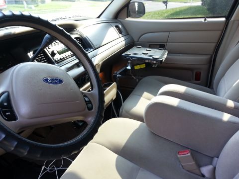 2004 Ford Crown Victoria - The interior of a 2004 Ford Crown Victoria, a Ford steering wheel and a mounted laptop desk.