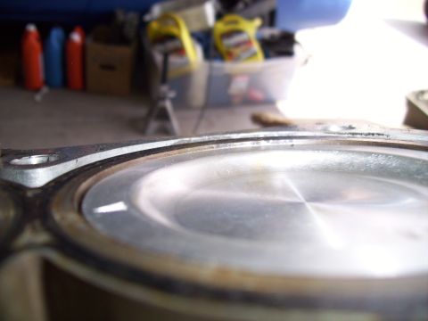 1995 Ford Probe - Close-up of an engine piston top, showing wear and a metallic sheen.