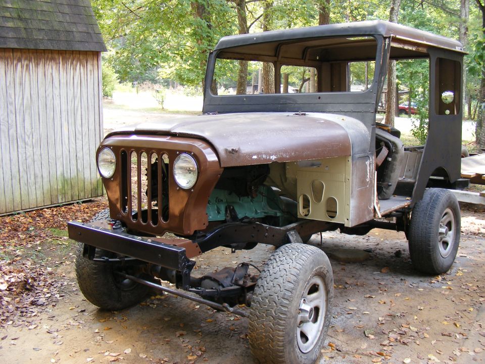 Jeep CJ-5 body, missing hood and fenders, with rust damage. Turquoise engine visible
