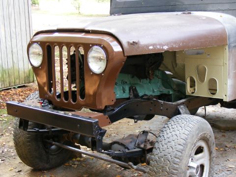 Front end of a Jeep CJ-5, showing the grille, headlights, and part of the engine. It's a project vehicle