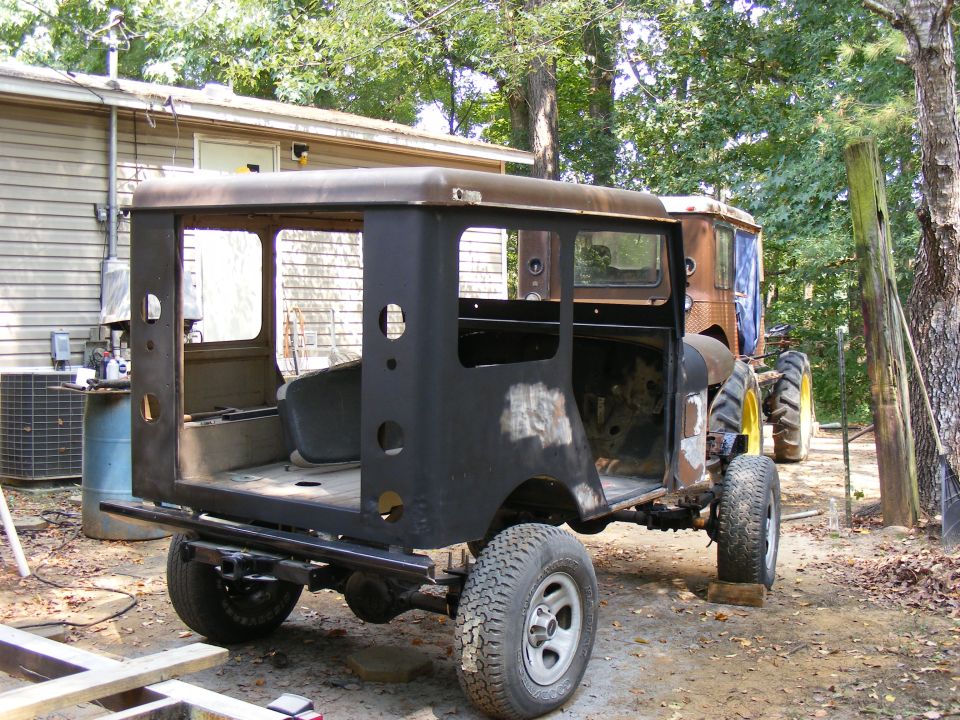 Black SUV body with exposed interior, rear view, on dirt ground