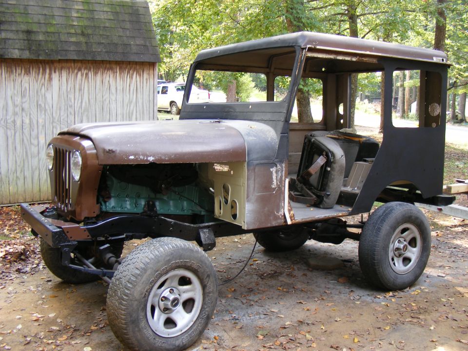 Jeep CJ-5 body, brown and black, missing hood and fenders, parked outdoors