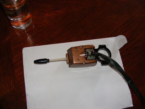 Turn signal switch assembly with black lever and copper-colored housing, resting on a white paper