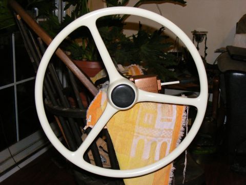 White three-spoke steering wheel with black center cap, resting on a yellow towel
