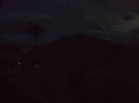 2009 Kenworth T800 - A dimly lit desert scene at dusk features mountains, a lone palm tree, and a building with illuminated windows.