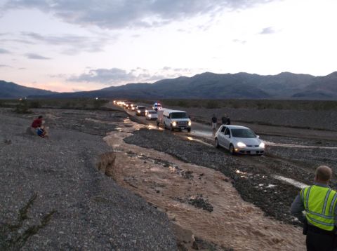 2009 Kenworth T800 - A convoy of vehicles navigates a water-filled desert wash at dusk.