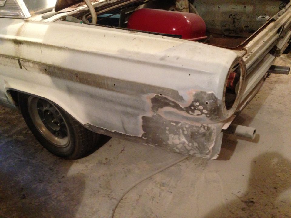 1964 Ford Fairlane front fender with body filler and primer, showing wheel well and part of the headlight opening