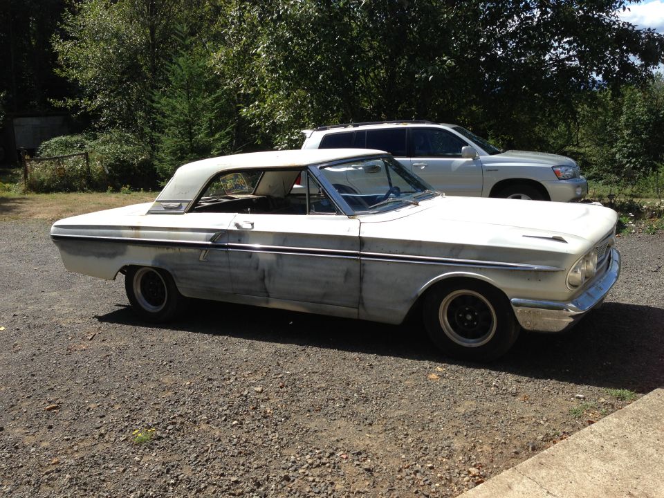 White 1964 Ford Fairlane coupe with primer patches on the side