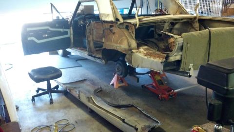 1964 Ford Fairlane - A 1964 Ford Fairlane is undergoing deconstruction, with its body raised on jacks and various parts removed.