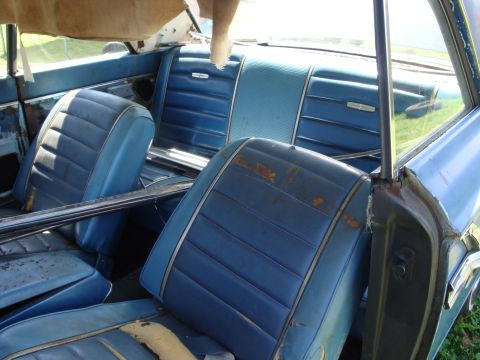 1964 Ford Fairlane - Interior view of a 1964 Ford Fairlane, showing its blue vinyl seats and signs of wear.