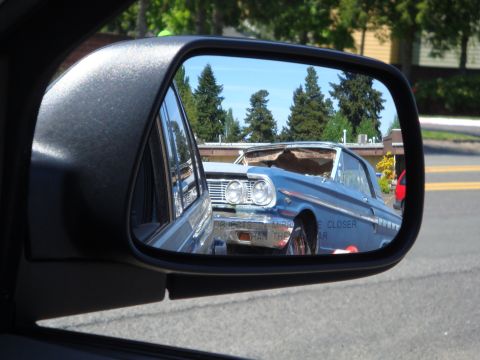 1964 Ford Fairlane - Reflection shows a classic blue car with a dented roof, seen through a side mirror.