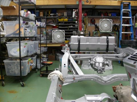 1976 Chevrolet Corvette - The chassis of a car is shown in a workshop, with a fuel tank and rear differential assembly.