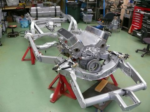 1976 Chevrolet Corvette - The chassis and engine of a Corvette are displayed on red stands in a workshop.