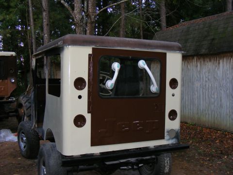 Rear view of a custom off-road vehicle with brown and cream paint, showing the back window and tires.