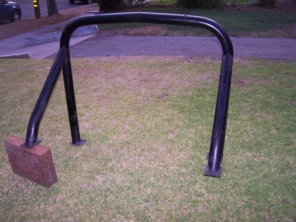 Black metal roll bar on grass with wooden support