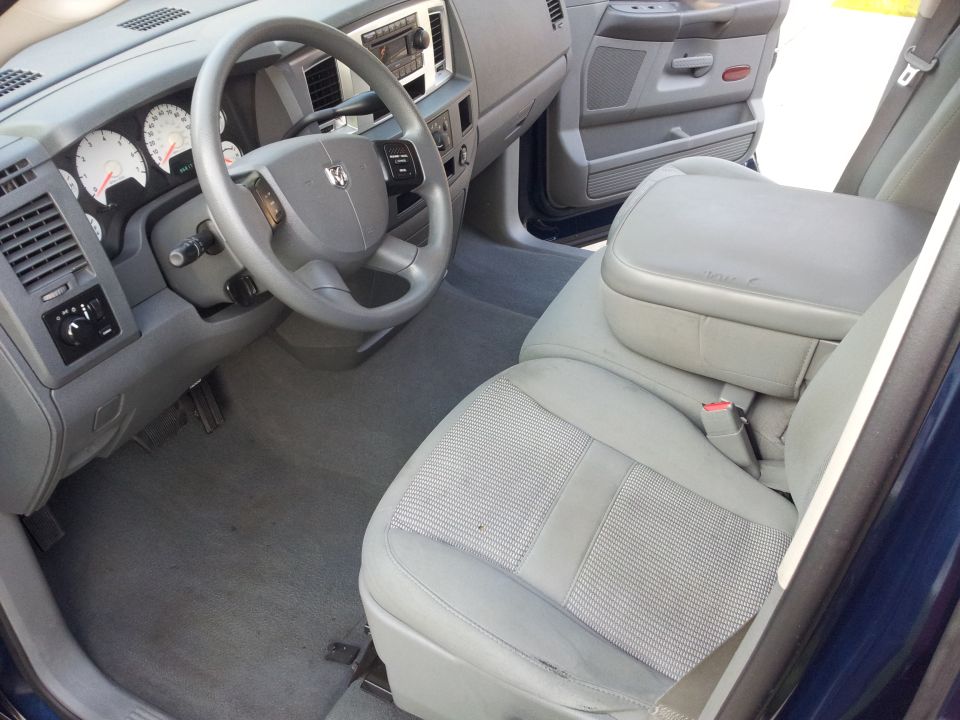 Interior of a blue Dodge Ram pickup truck, showing dashboard, steering wheel, and front seats.