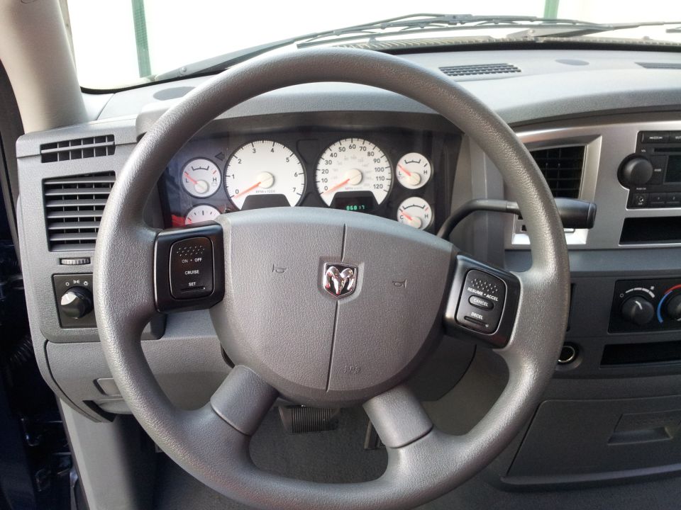 Interior of a Dodge Ram pickup truck, showing steering wheel, dashboard, and gauges.