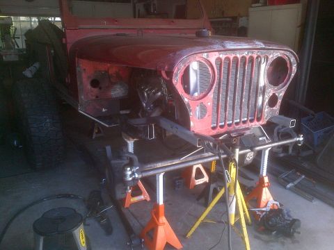 1985 Jeep CJ7 - This 1985 Jeep CJ7 is shown in a workshop setting, supported by jack stands as it appears to be undergoing restoration or modification.