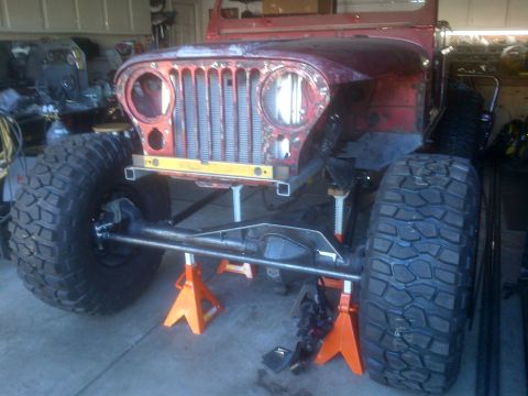 1985 Jeep CJ7 - This Jeep CJ-series chassis is elevated on jack stands, showing its front end and suspension components during a build.