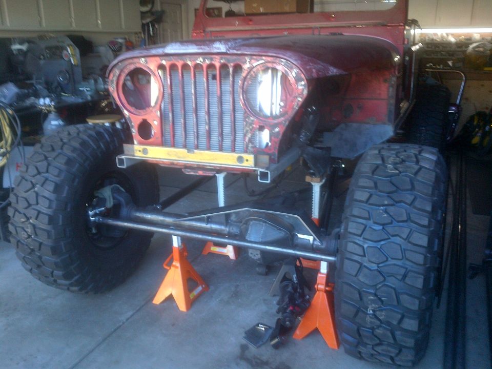 Jeep CJ-series chassis on jack stands, front view, red body