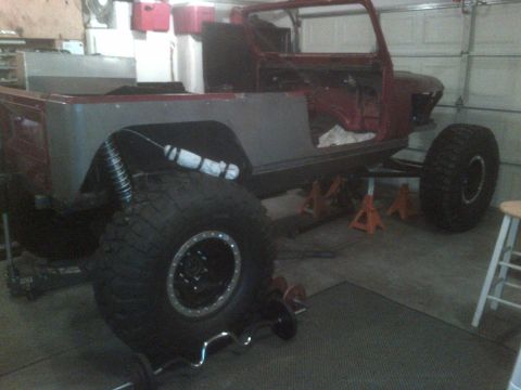 1985 Jeep CJ7 - This Jeep CJ7 body is undergoing modifications and is supported by jack stands, large off-road tires.